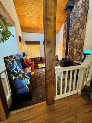 Uma sala de estar acolhedora com lareira, teto de madeira e parede de pedra.