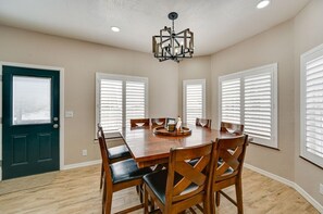 Une salle à manger avec une table en bois, six chaises et un lustre.