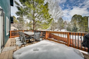 Une terrasse couverte avec une table et des chaises, une terrasse en bois et un sol recouvert de neige.