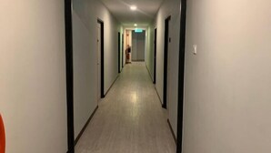 Een lange, smalle gang met deuren aan beide kanten, die leidt tot een kamer aan het einde.