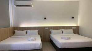 Twee enkele bedden met witte lakens, een houten hoofdbord en een wandairconditioner.