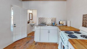 A compact kitchen with a white stove, a microwave, and a sink.
