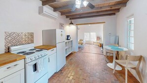 A kitchen with a stove, refrigerator, and wooden ceiling beams.