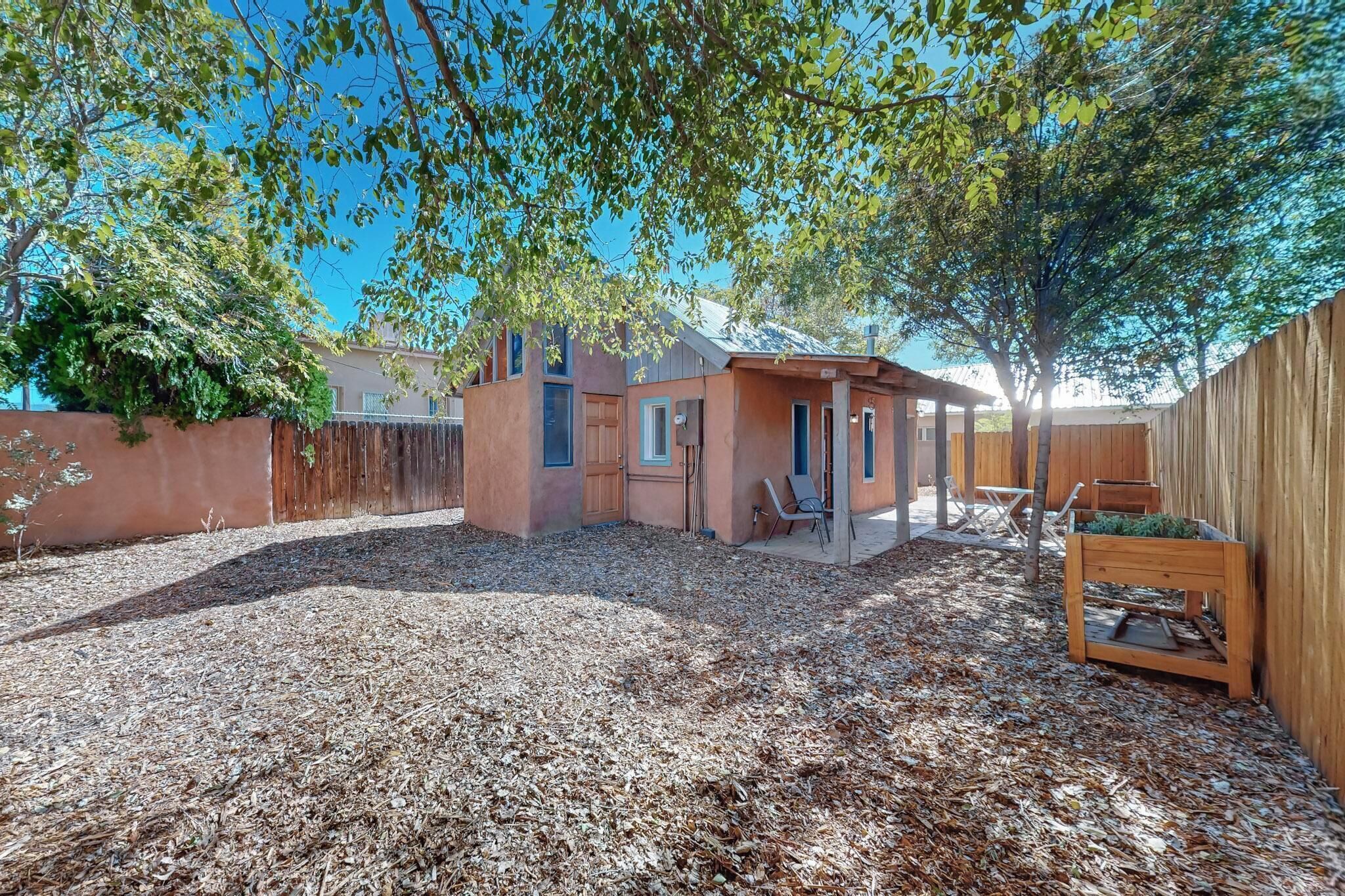 A backyard with a wooden fence, a small wooden structure, and a tree providing shade.