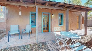A rustic building with a wooden pergola, a brick patio, and outdoor seating.
