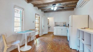 A kitchen with white cabinets, a white refrigerator, and a ceiling fan.