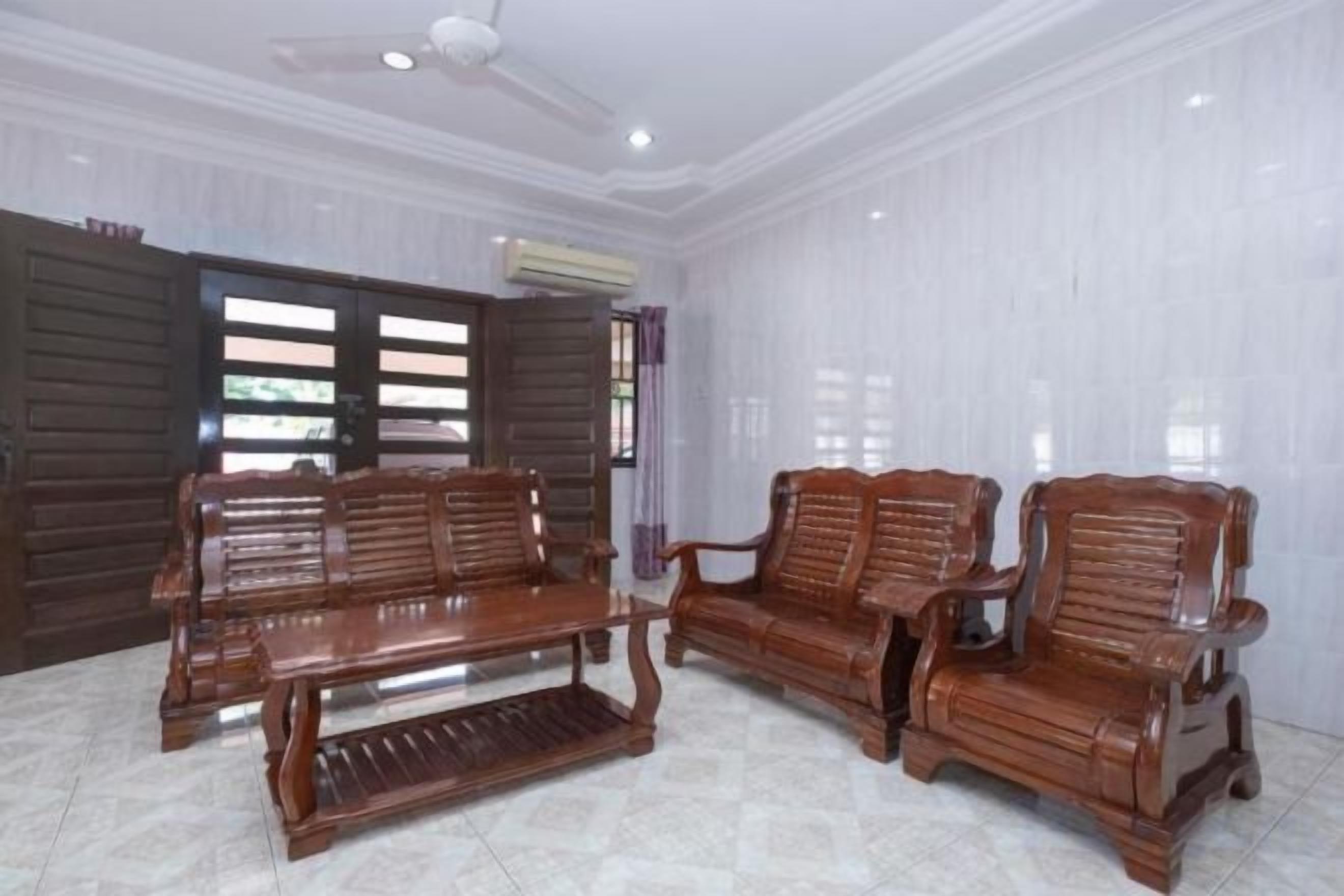 A room with a ceiling fan, a wooden sofa set, and a tiled floor.