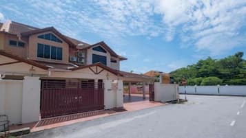 A two-story house with a gated driveway and a clear sky.