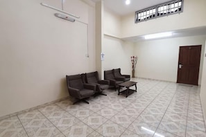 A waiting area with a reception desk, two sofas, a coffee table, and a door. - Rivermoon Kuantan (Kuala Kuantan)