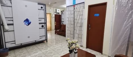 A hotel lobby with a reception desk, a large air conditioning unit, and a door with a blue sign.