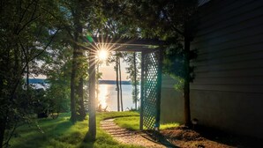 A pathway leading to a wooden pergola with a view of a lake at sunset. - Lakefront Suite - Spa, Firepit, Kayaks & PBall (Macon)