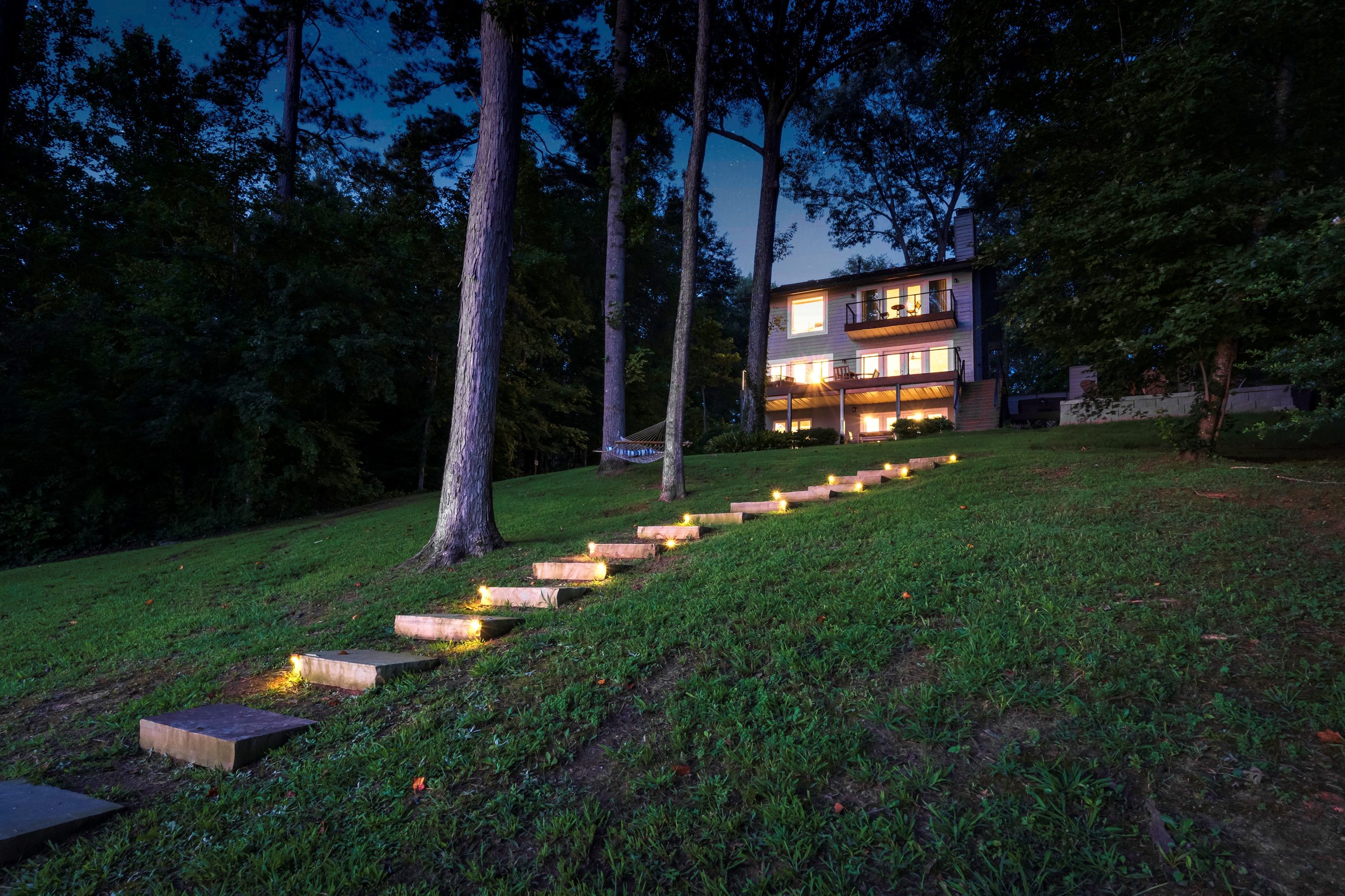A modern house with a well-lit staircase leading up to a balcony.