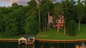 A lakeside house with a dock and a small boat house. - Lakefront Suite - Spa, Firepit, Kayaks & PBall (Macon)