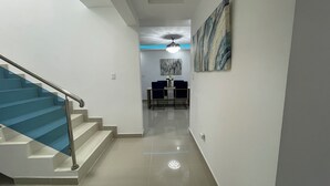 A hallway with a staircase, a dining area with a table and chairs, and a ceiling fan.
