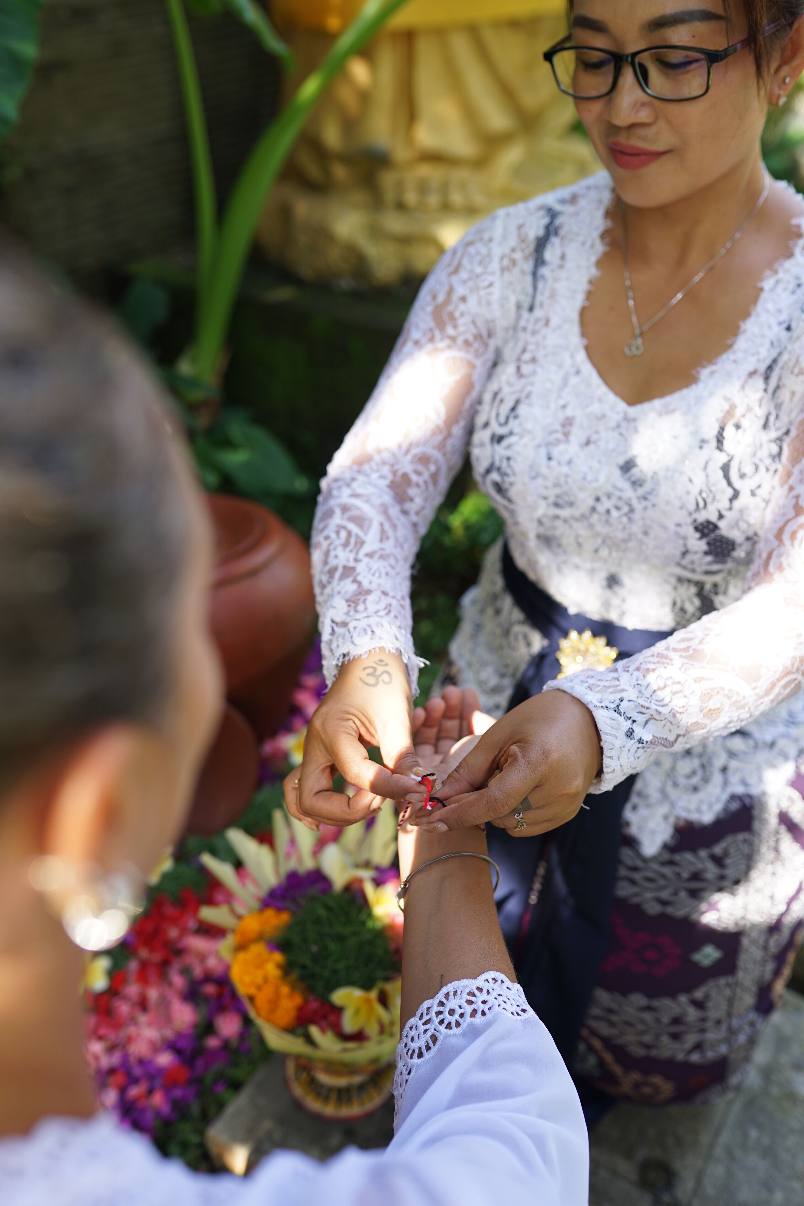 Iemand voert een ritueel uit met bloemen en een klein voorwerp.