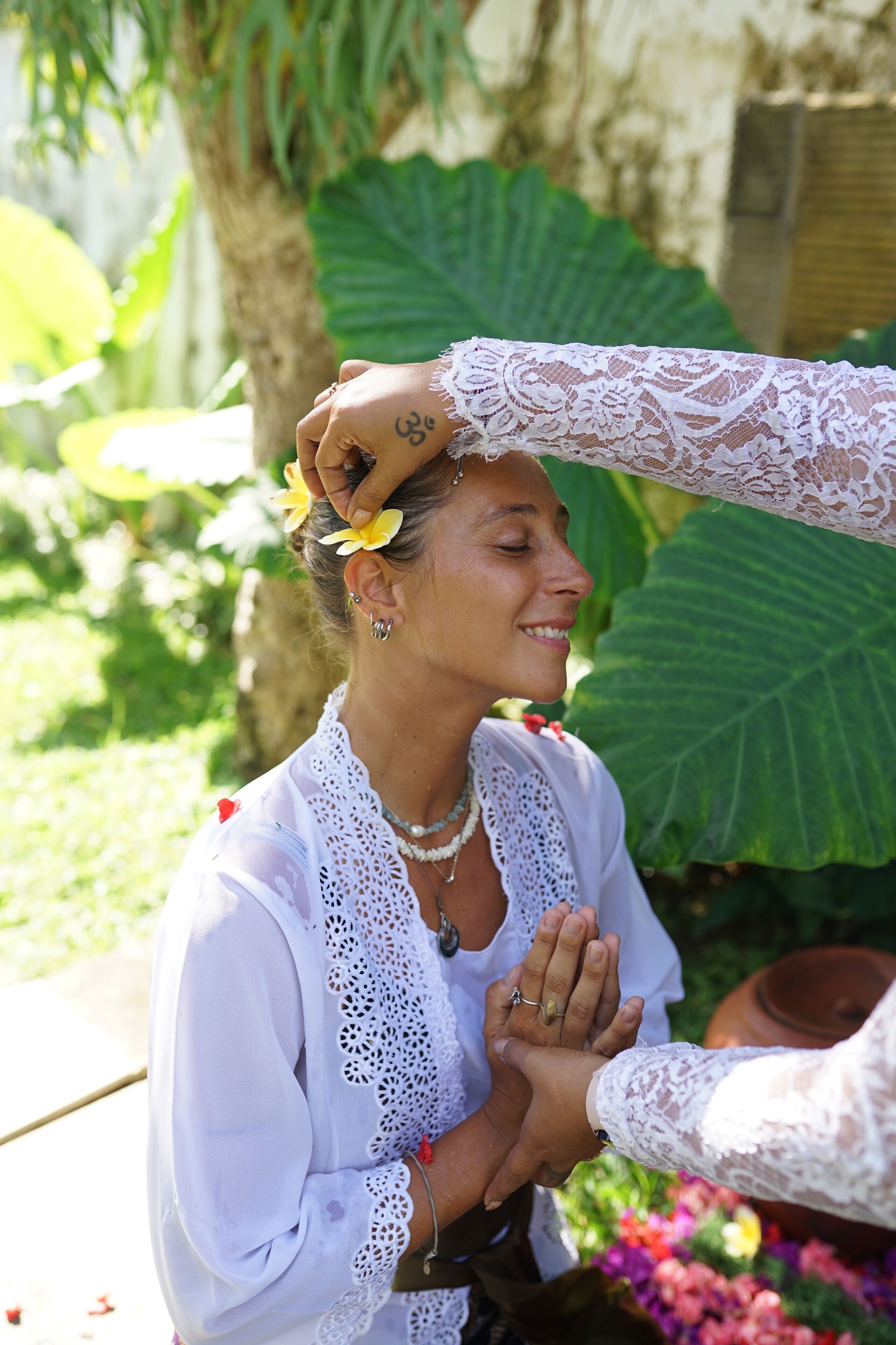 Una persona vestida con una prenda blanca de encaje y un adorno floral en el cabello.