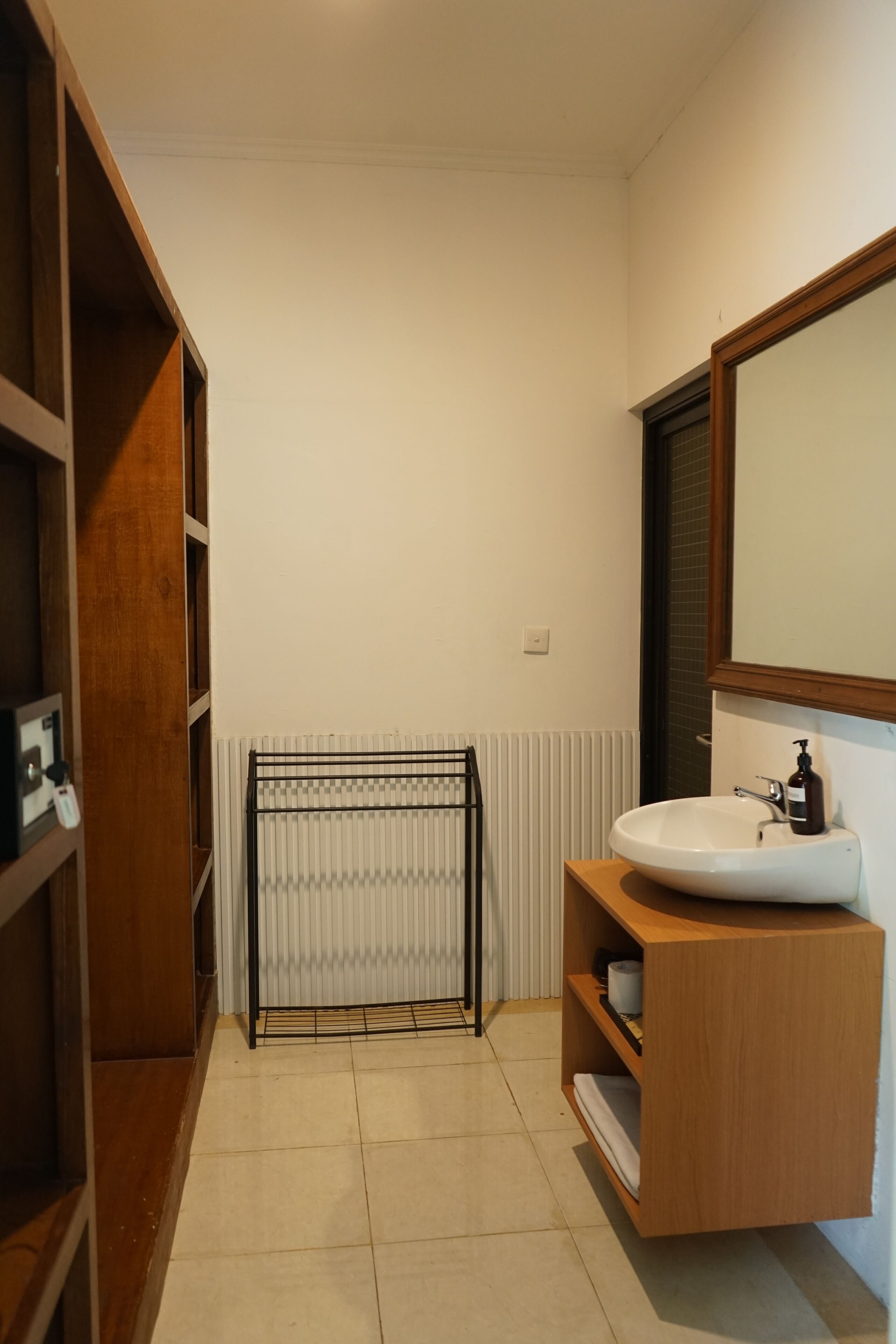 A modern bathroom with a wooden vanity, a large mirror, and a radiator.