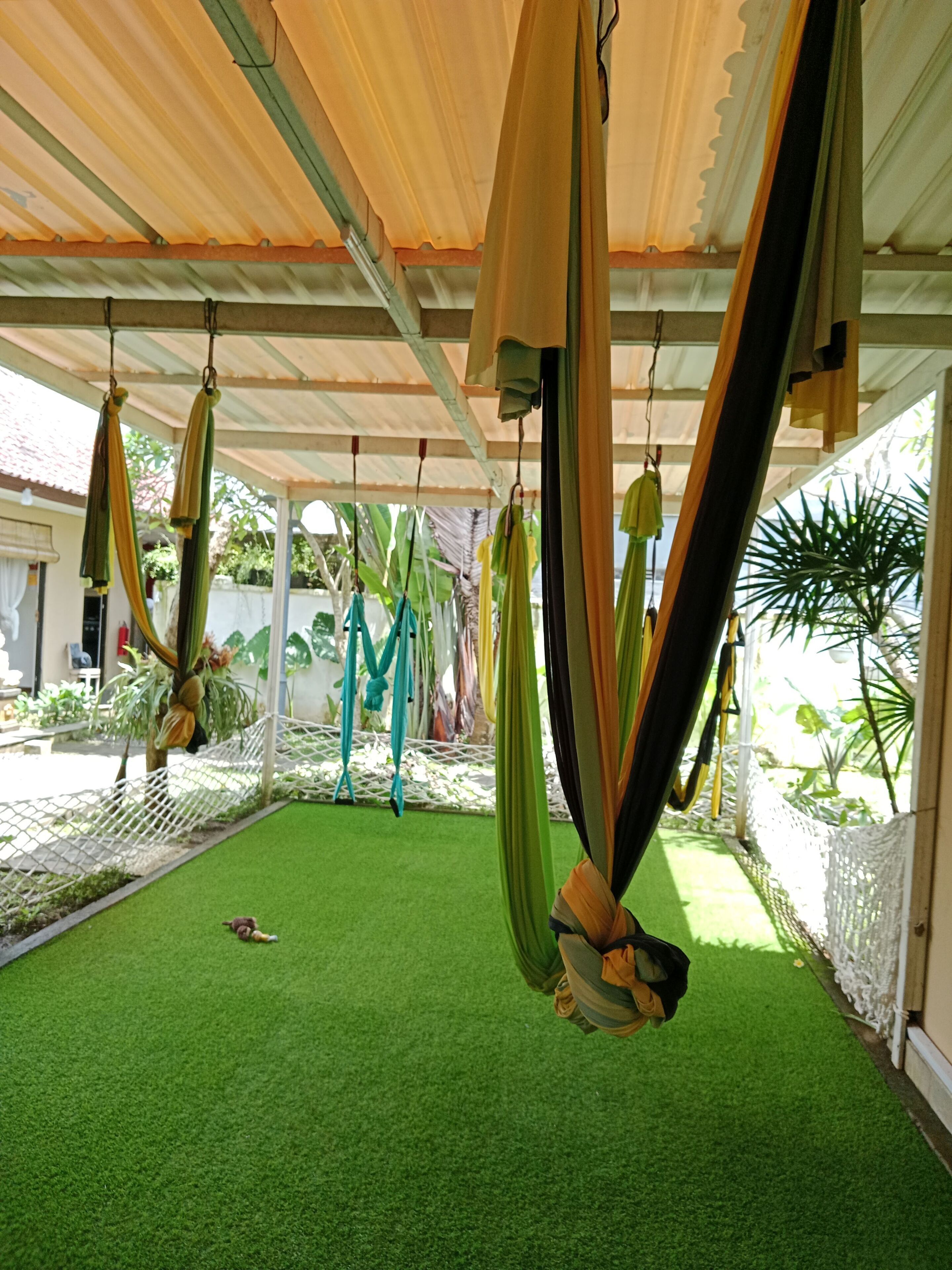 A covered outdoor area with hanging hammocks and artificial grass.