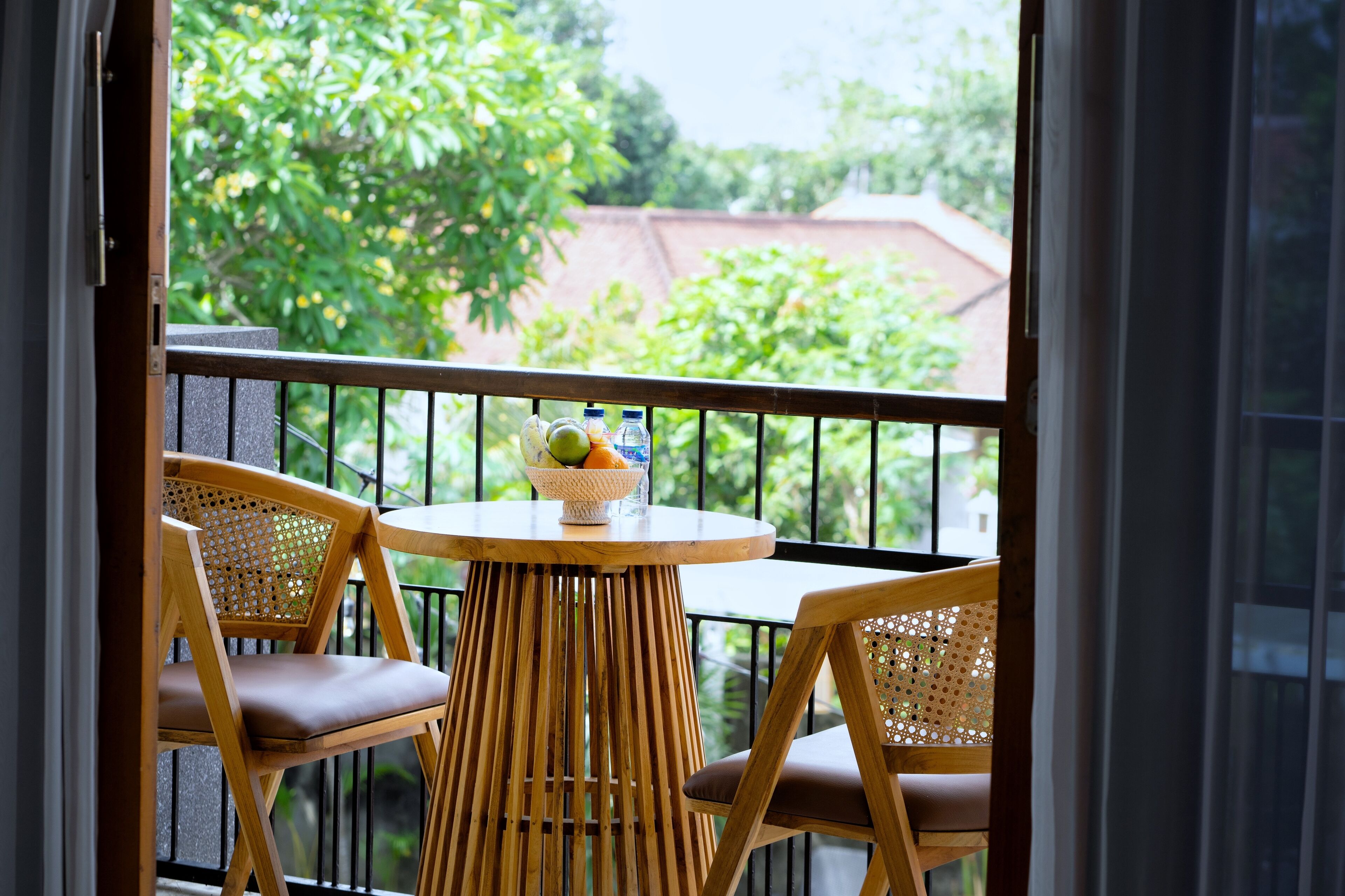 A balcony with two wicker chairs and a small round table with a fruit bowl.