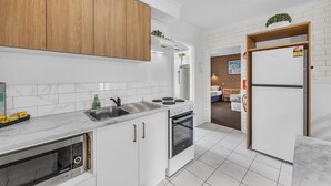 Una cocina moderna con armarios blancos, horno empotrado y refrigerador.