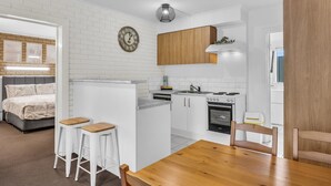Una cocina moderna con paredes de ladrillo blanco, armarios de madera y una zona de comedor con mesa y taburetes.
