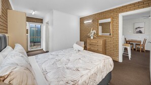 Un dormitorio con una cama grande, un aparador, un espejo y un comedor con mesa y sillas.