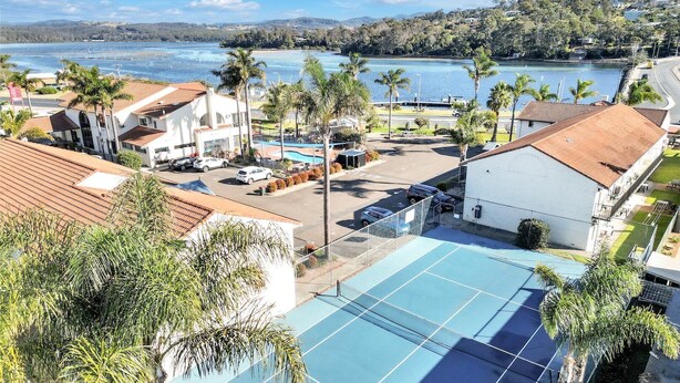 Un hotel frente al mar con piscina, palmeras y vistas al océano.