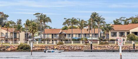Un hotel frente a la playa con edificios de varios pisos, una playa de arena y una señal de límite de velocidad.