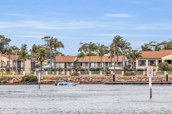 A beachfront hotel with multiple-story buildings, a sandy beach, and a speed limit sign.