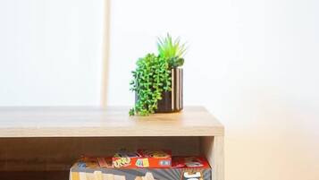 A television displaying a Netflix logo, a small potted plant on a shelf, and a wooden box with a game on a table.