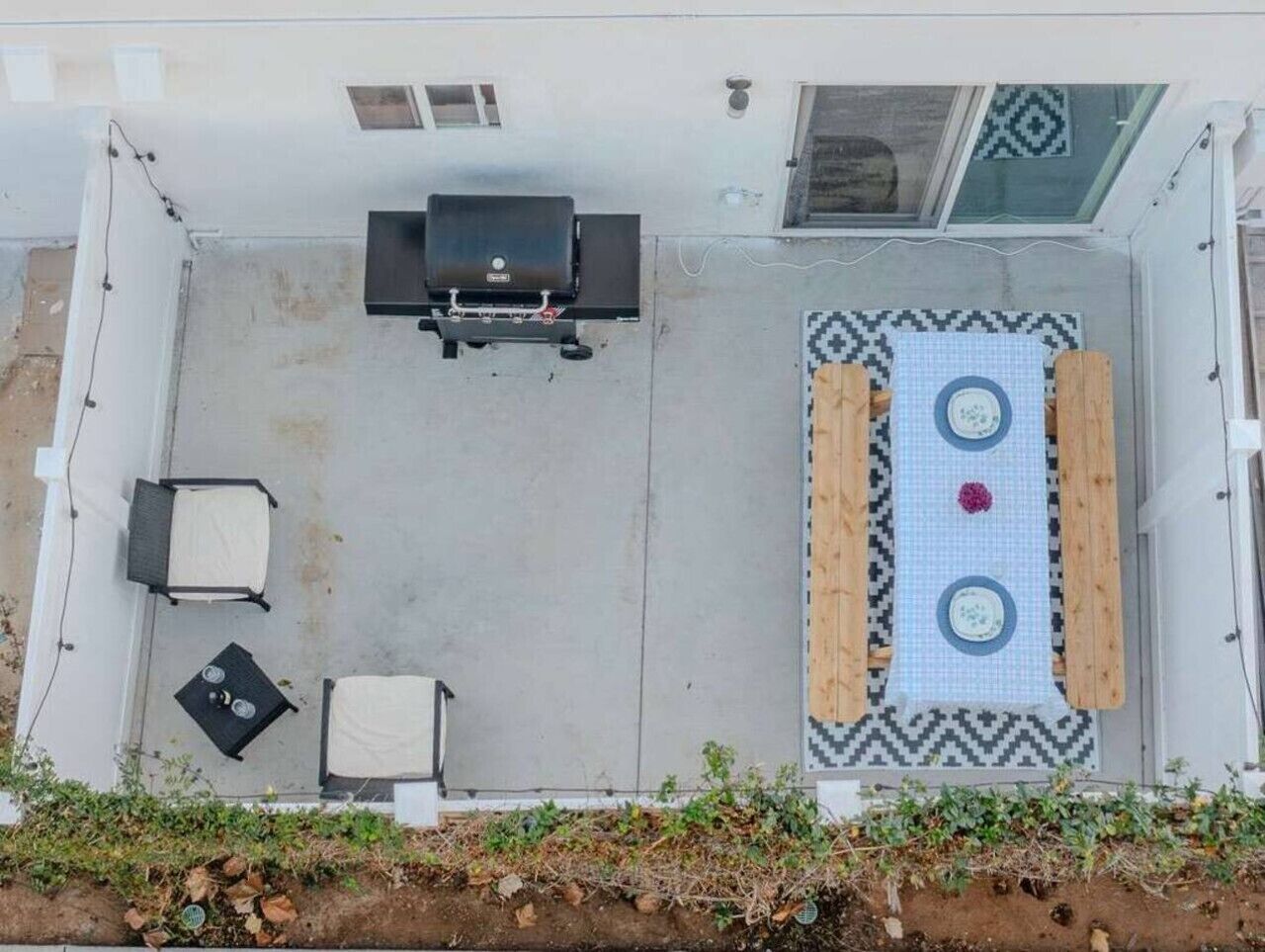 Eine Dachterrasse mit Grill, zwei Stühlen, einem Tisch und einem gemusterten Teppich.