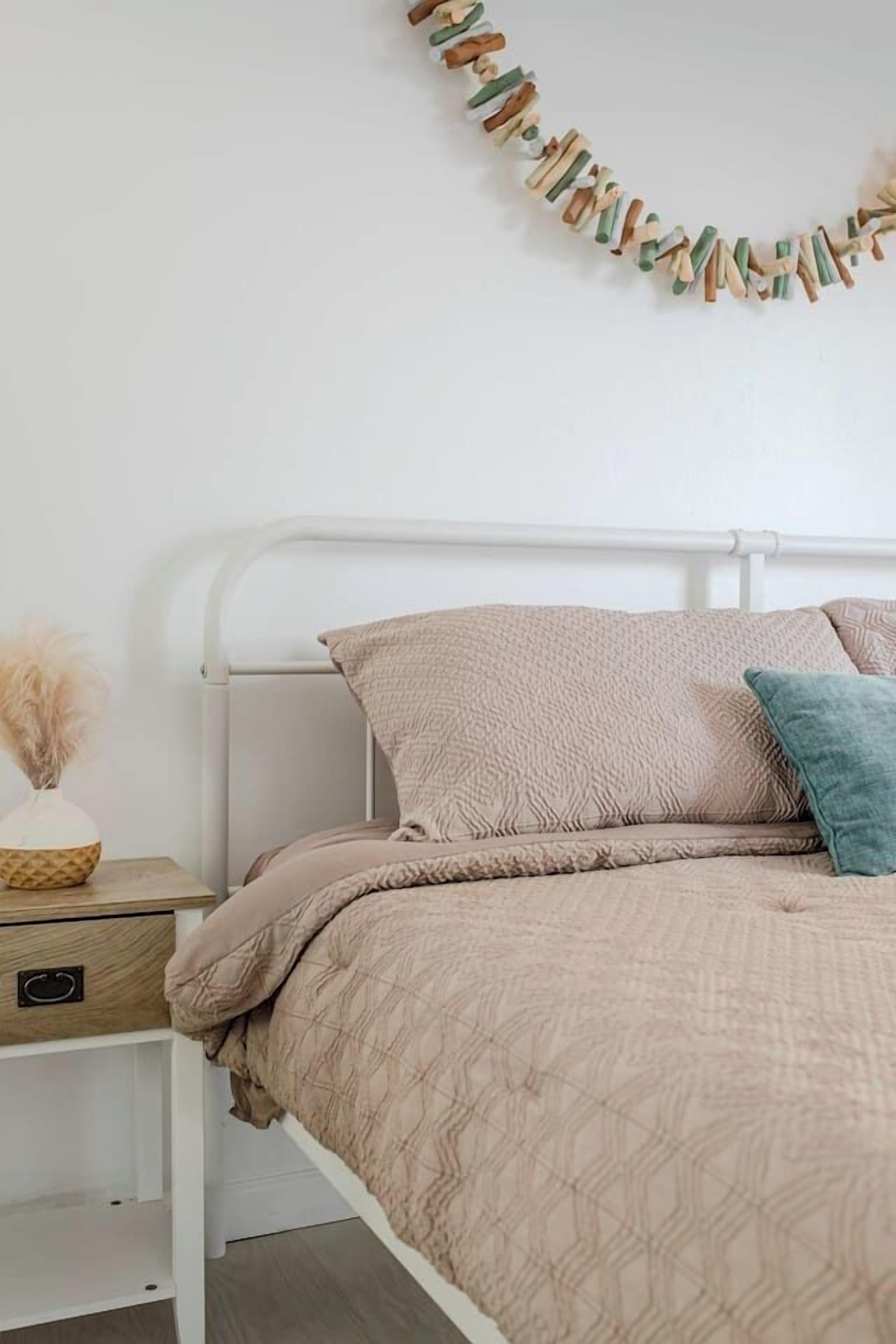 Un lit avec un cadre en métal blanc, une literie beige et une décoration murale.
