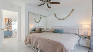 Una camera da letto con un letto, comodini, una ventola a soffitto e uno specchio.