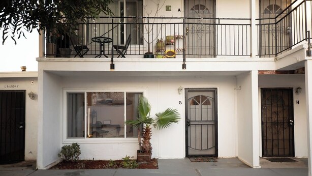 Un edifici residencial de dues plantes amb un balcó, una porta amb la lletra 'G' i una finestra que dona a l'interior.