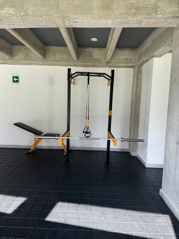A gym with a pull-up bar, bench, and weight rack.