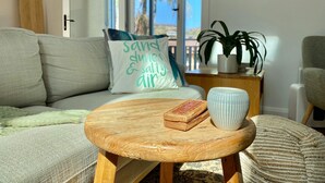 Un salon comprenant un canapé, une table basse, une planche de surf et une décoration murale représentant des poissons.