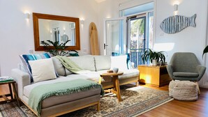 Un salon chaleureux avec un canapé, une table basse, un fauteuil, un tapis et une décoration murale représentant des poissons.
