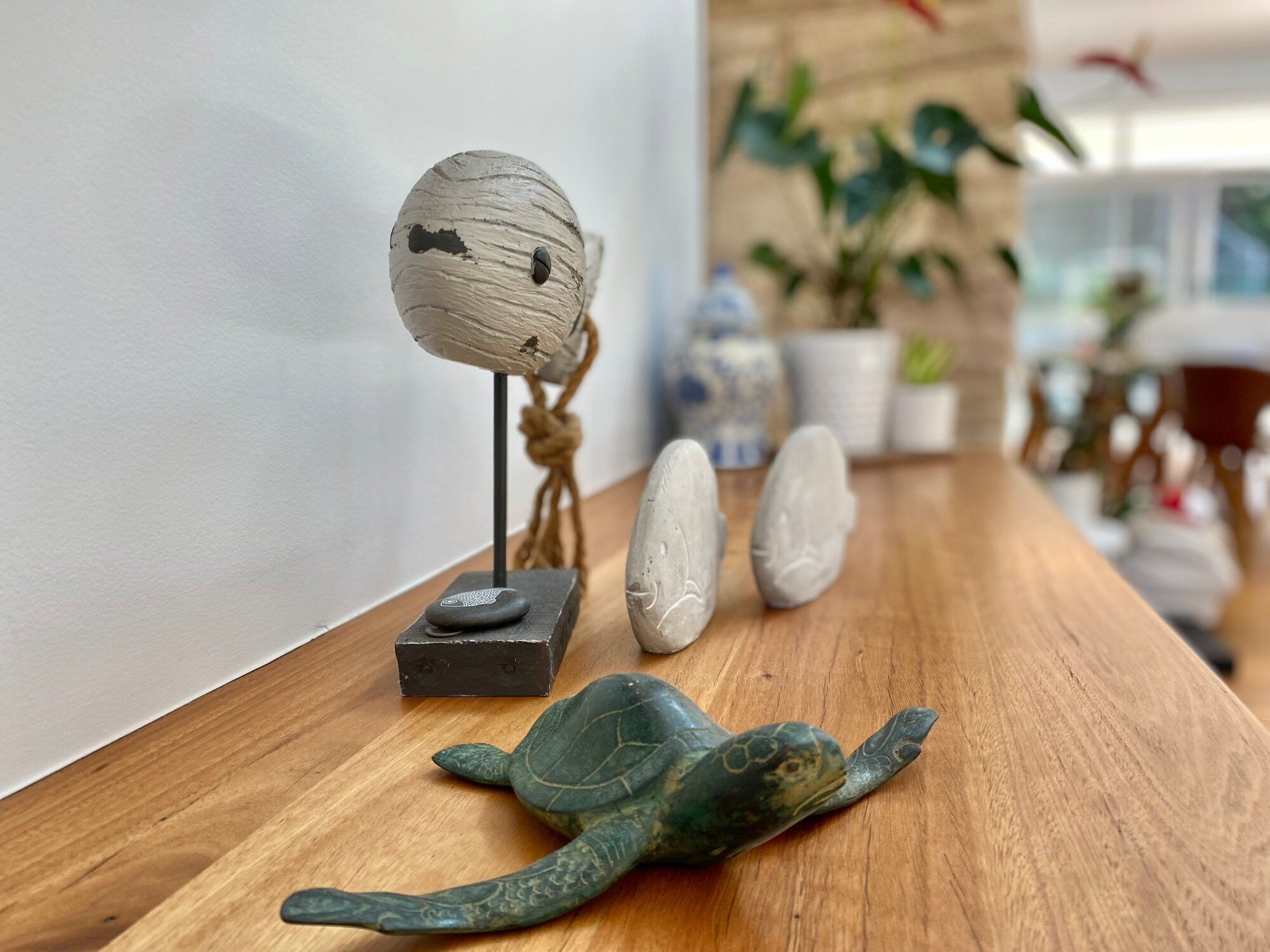 A wooden table with a decorative turtle sculpture, a small wooden figure, and a stone.