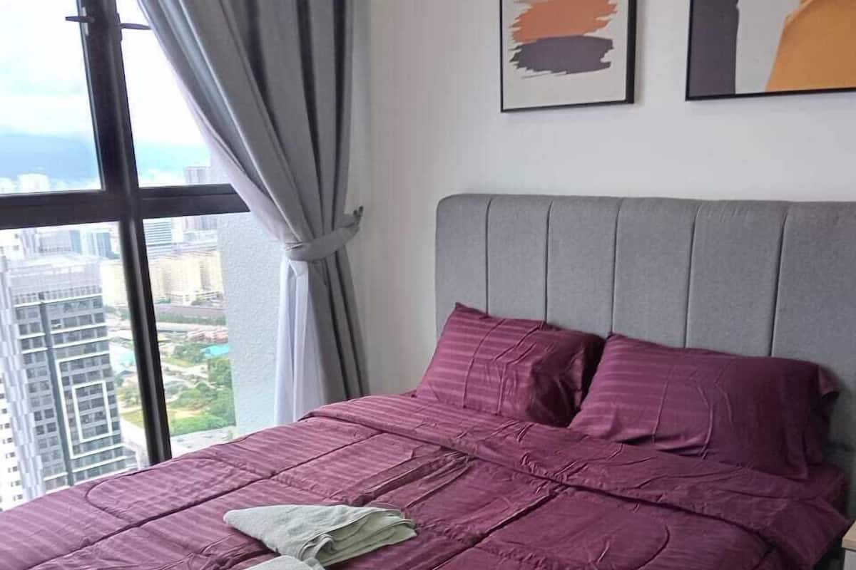 Un dormitorio con una cama grande, cabecera gris y ropa de cama morada.