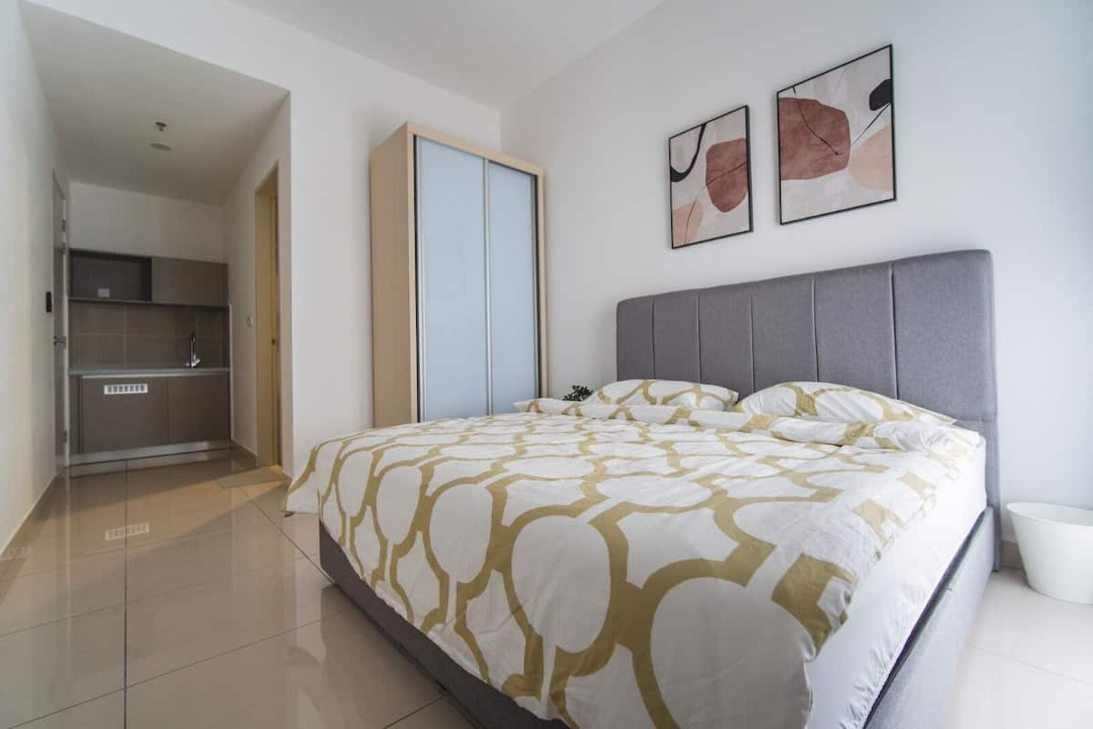 Una habitación de hotel moderna con una cama grande, un cabecero gris y dos cuadros abstractos en la pared.