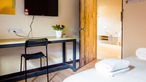 A hotel room with a bed, a desk with a chair, a television, a plant, and a bathroom visible through an open door. - Plumeria 4BR Garden House by uBook (Butterworth)