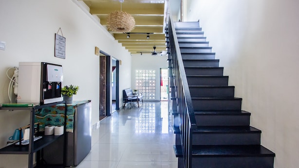 A modern kitchen with a refrigerator, sink, and a coffee machine. There is a staircase leading to another floor. - Plumeria 4BR Garden House by uBook (Butterworth)