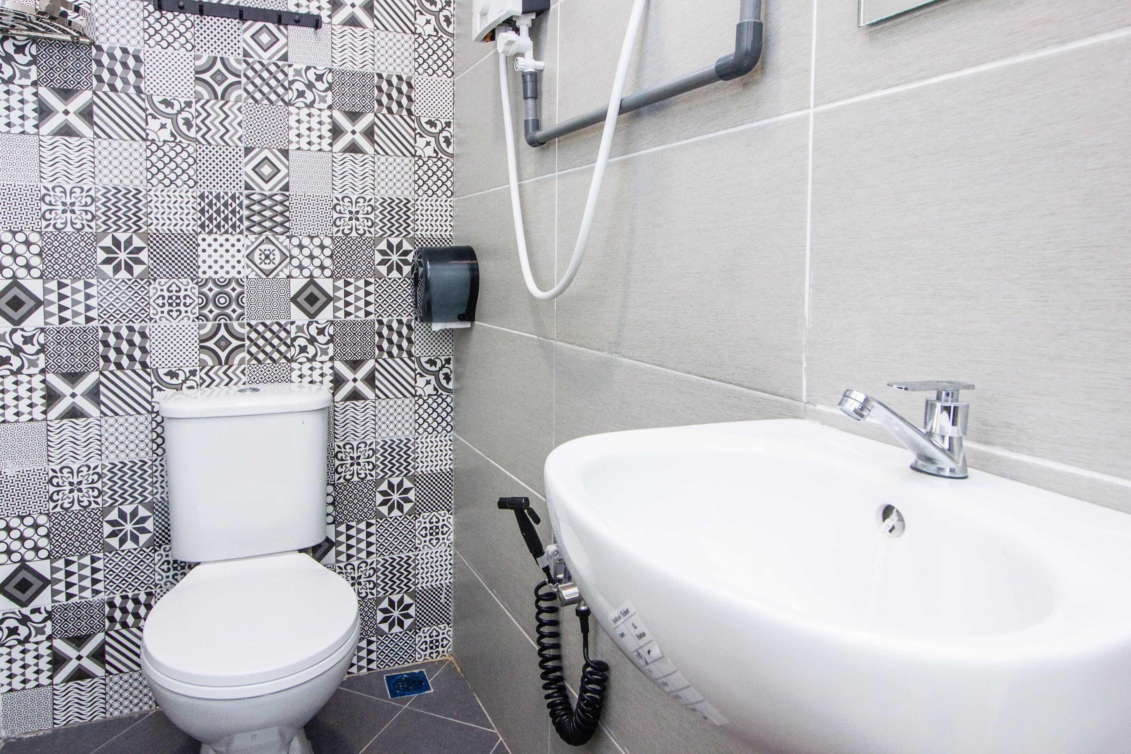 A bathroom with a toilet, a sink, and a patterned wall.