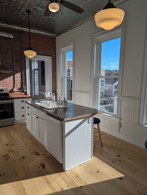 A kitchen with a large island, wooden flooring, and a view of the city through large windows. - 2 Min to RPI Modern Space + Fast WiFi (Troy)