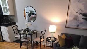 A living room with a dining area, a coffee machine, a lamp, a couch, and a painting on the wall. - A Pleasant Stay (Oak Park)