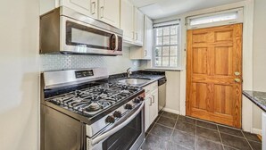 A kitchen with a gas stove, oven, microwave, and stainless steel sink. - A Pleasant Stay (Oak Park)