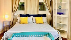 A bedroom with a bed, bedside tables, a bench, a shelf, and a window with curtains.