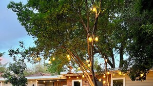 A backyard with a hot tub, outdoor seating, and string lights.