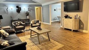 Un salon comprenant un canapé, des fauteuils, une table basse et un téléviseur.