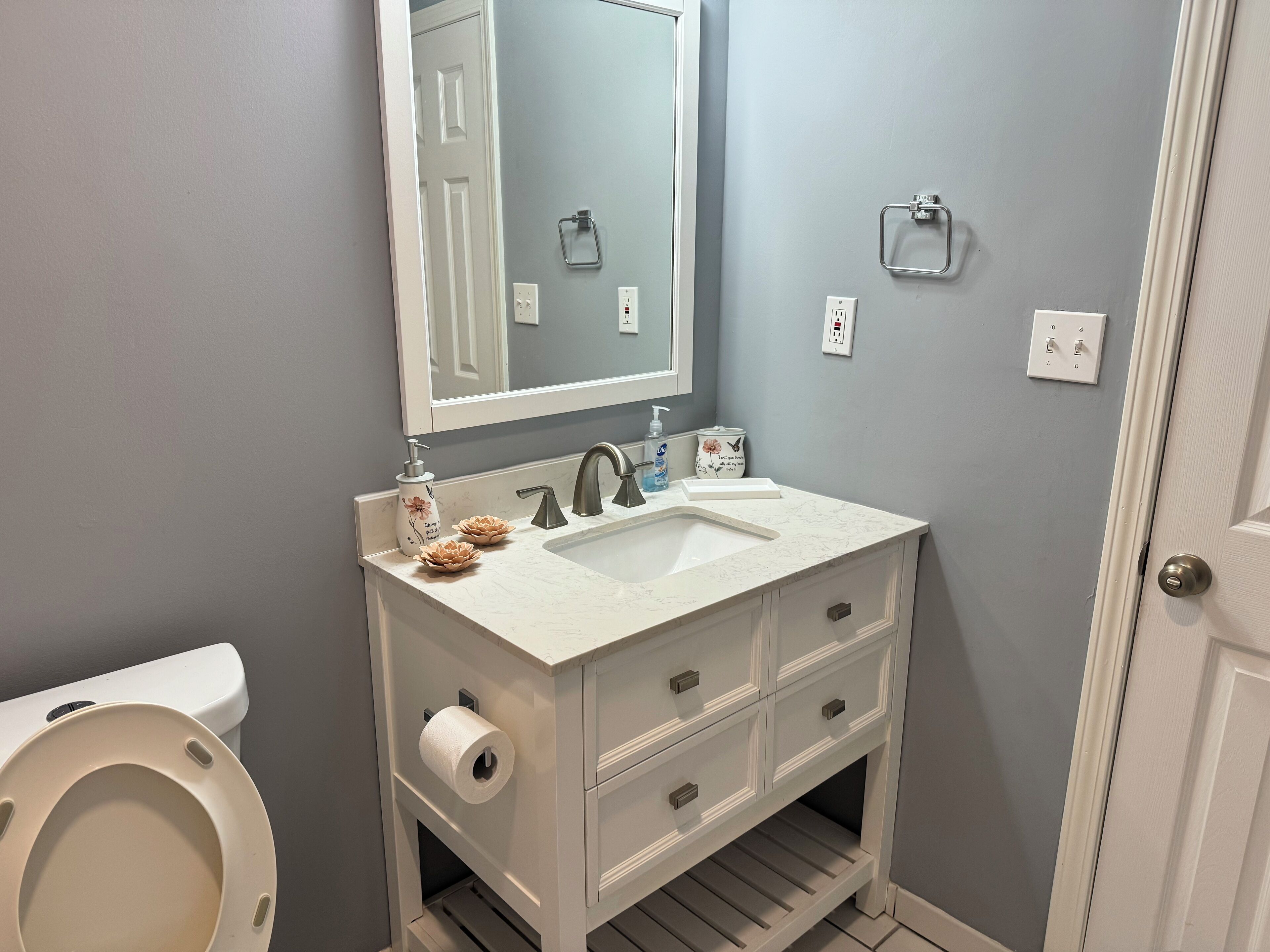 Un bagno con un mobile lavabo bianco, uno specchio, un water e un lavandino.